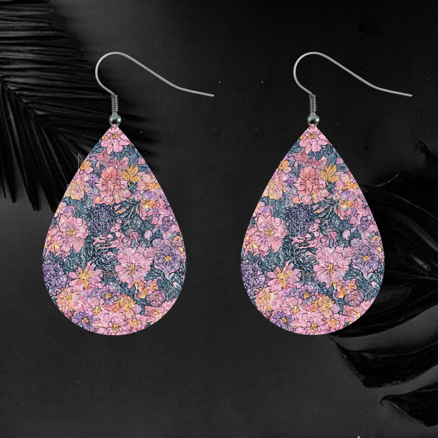 Teardrop earrings with a pink, purple, and yellow floral pattern on a black background.