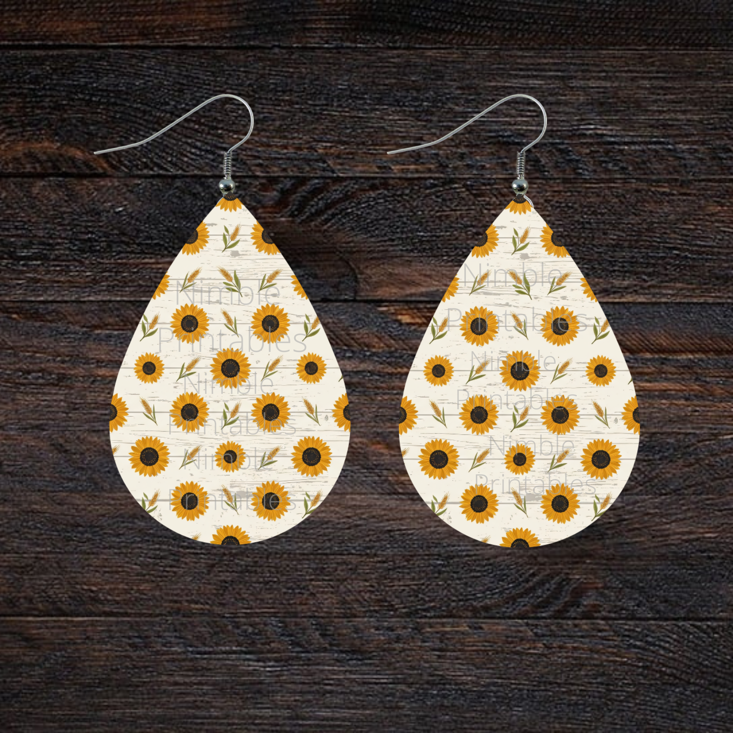 Teardrop earrings with a scattered sunflower and wheat pattern on a wood-grain background.
