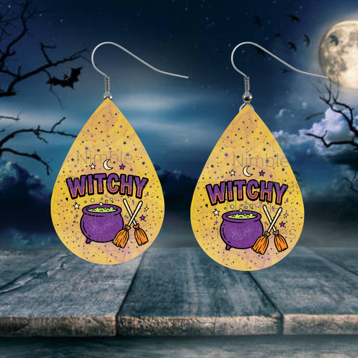 Teardrop earrings with "Witchy" text, cauldron and broom design, on a dark background.