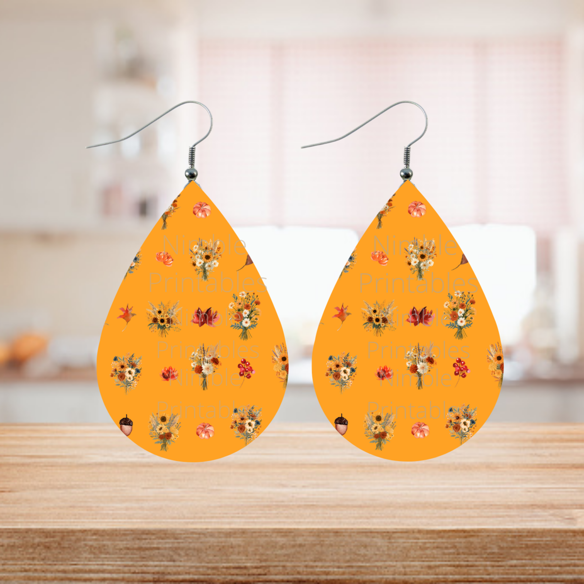 Teardrop earrings with fall floral pattern and watermarks on an orange background.