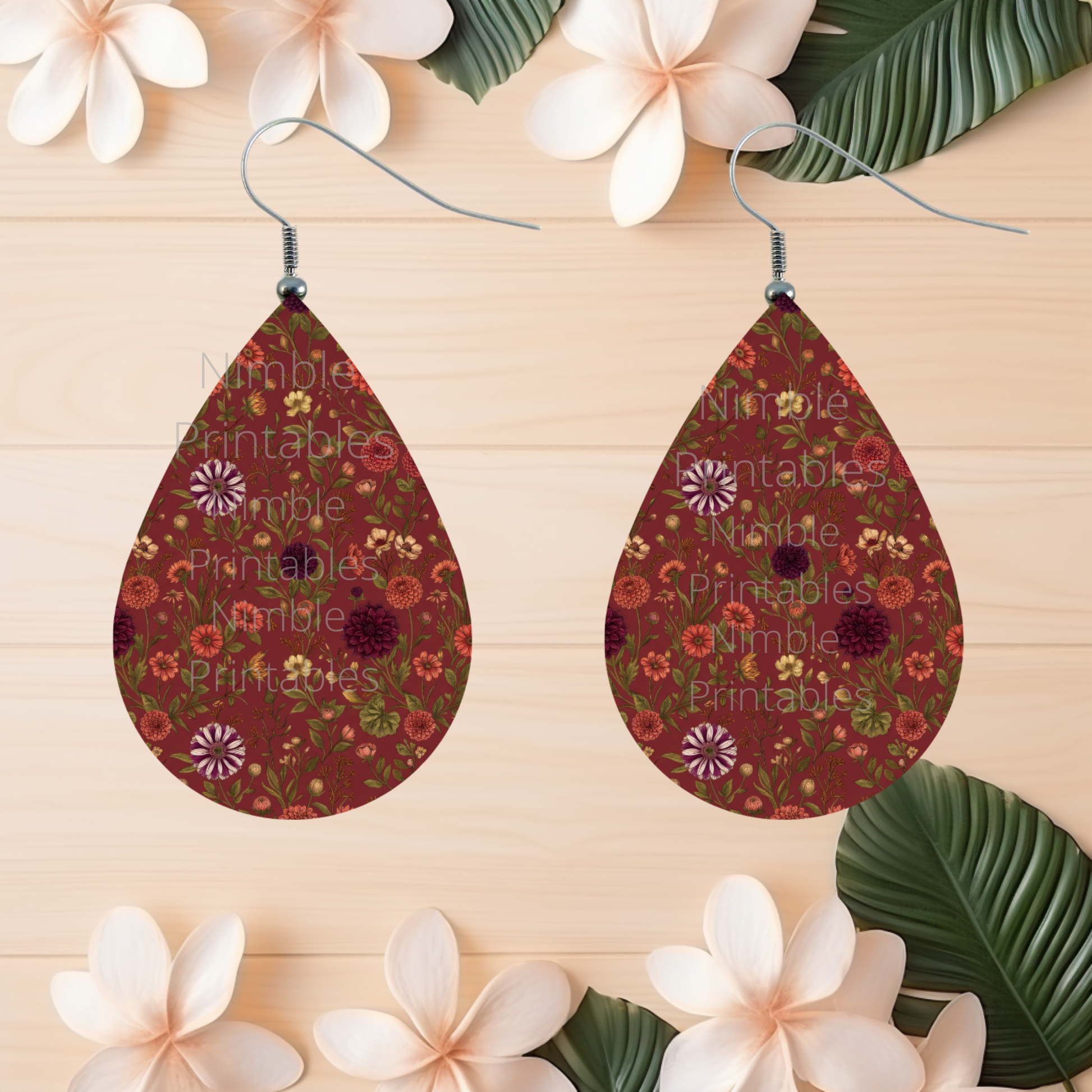 Teardrop earrings with a dark red floral pattern, featuring white tropical flowers and green leaves.