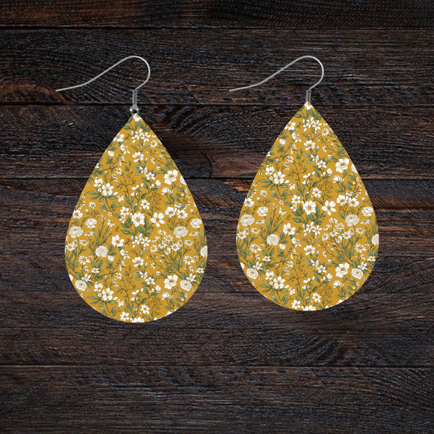 Teardrop earrings with a small white floral print on a mustard yellow background.