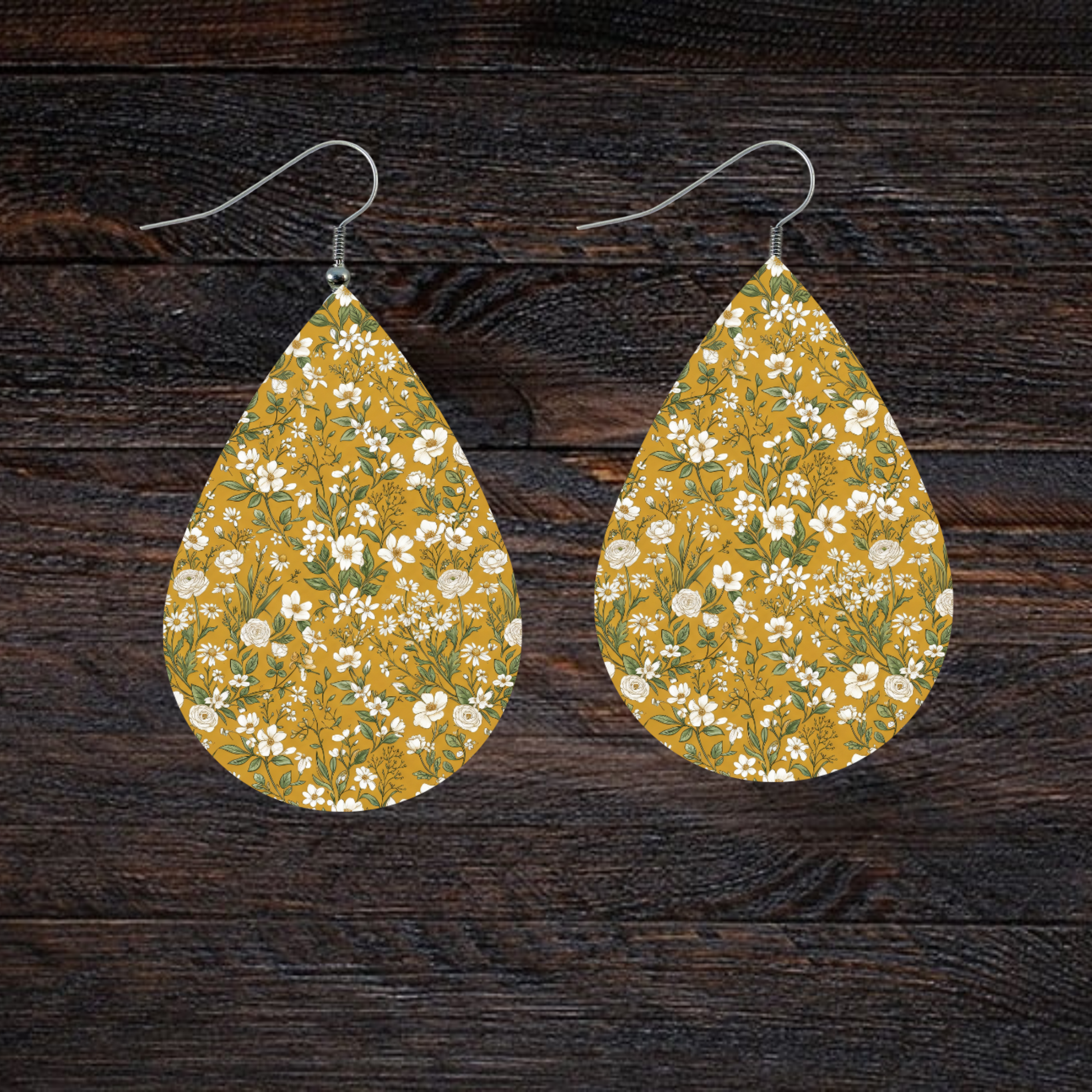 Teardrop earrings with a small white floral print on a mustard yellow background.