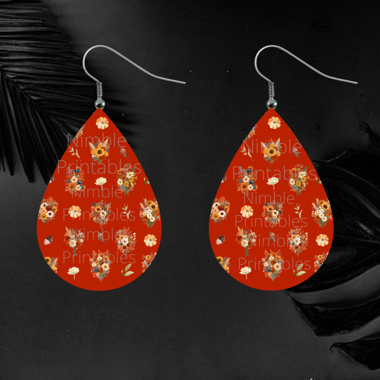 Teardrop earrings with a red background featuring a repeating pattern of autumn flowers and pumpkins.