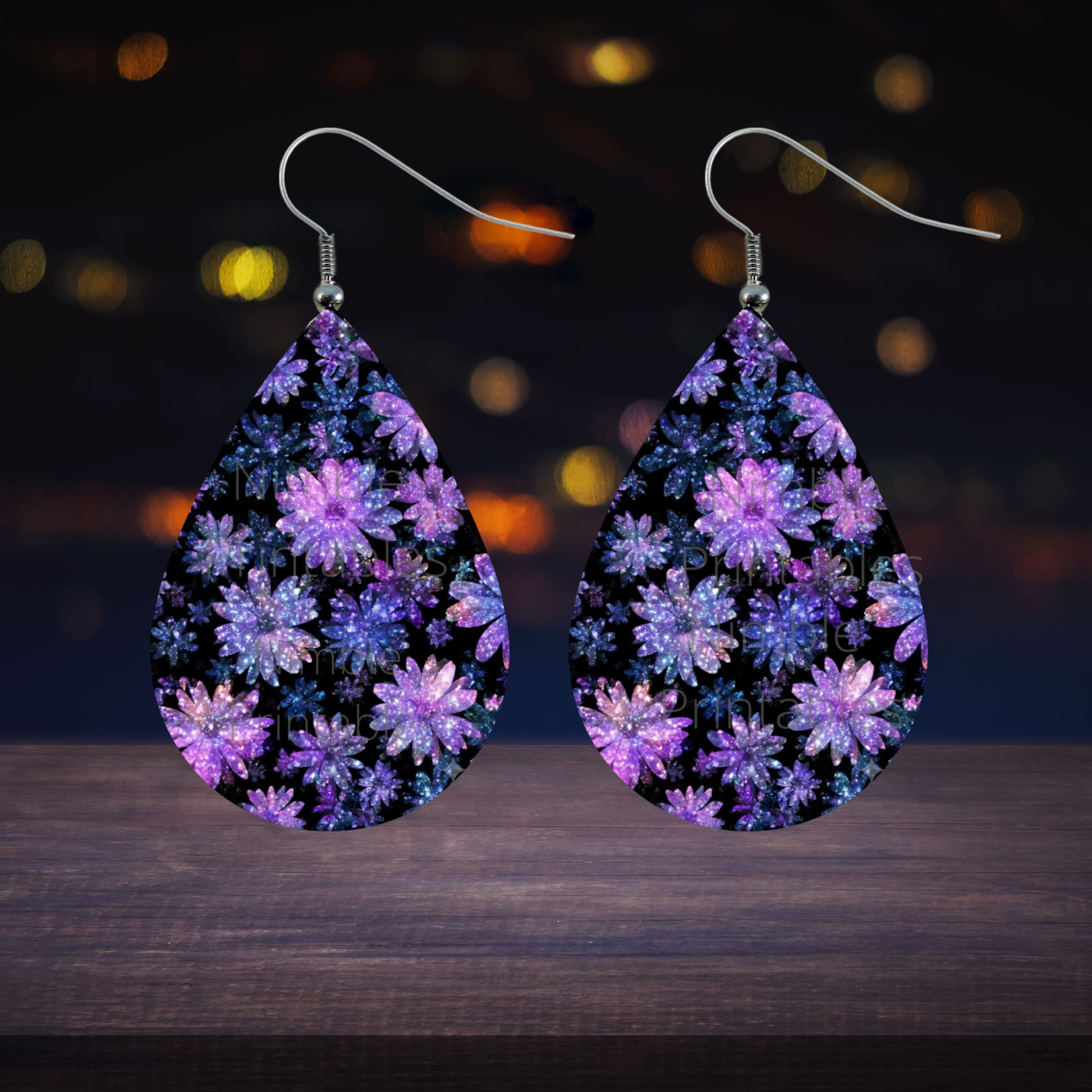 Teardrop earrings with a galaxy floral pattern against a bokeh background.